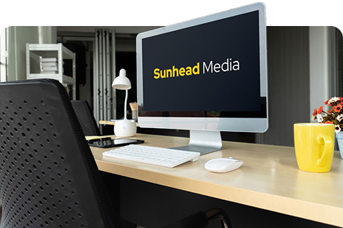 a desk with a computer monitor showing the Sunhead Media logo