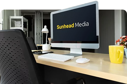 a desk with a computer monitor showing the Sunhead Media logo
