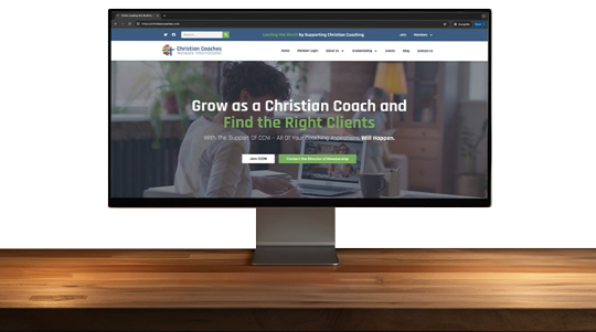 a desk with the christian coaches website shown on a computer monitor